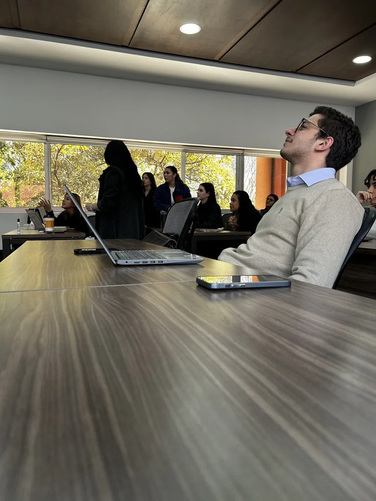 Estudiante de la FLDM piensa durante una clase, con companeros al fondo